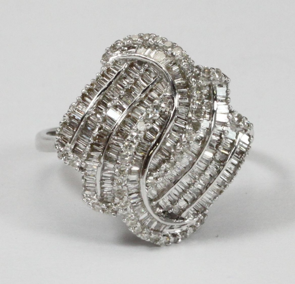 A 9ct white gold multi-row swirl design ring set with baguette and round brilliant cut diamonds. The