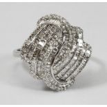 A 9ct white gold multi-row swirl design ring set with baguette and round brilliant cut diamonds. The