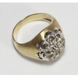 An unmarked yellow-metal nine-stone cluster diamond ring, claw-set to the centre with a RBC