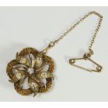 An Edwardian 10K gold brooch of pierced floral design, the centre set with a a round Victorian Cut