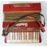 A red accordion by Geraldo with faux mother of pearl keys and leather straps, in black leather case