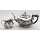 A silver teapot with shaped finial, ebonised handle and half-gadrooned body raised on four bun feet,