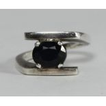 A white metal ring set with an inky blue sapphire coloured stone, tests as silver, interesting