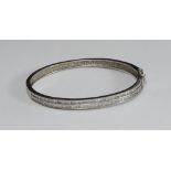 An 18ct white gold and clear stoned hinged bangle, channel set in two rows with 78 square cut
