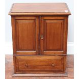 A small wooden table-top cabinet, the two panelled doors enclosing storage space, with two further