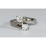 An 18ct white gold two-stone diamond ring, of cross-over design, RBC diamonds each estimated 0.