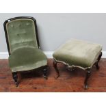 A Victorian ebonised nursing chair together with a rectangular footstool on cabriole supports,