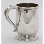 A small silver tankard with scroll handle raised on stepped circular base, 10cm high, approx. 5.19