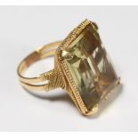 A yellow metal (tests as 18ct gold) ring, four claw set with a large rectangular citrine coloured