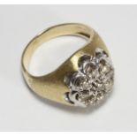 An unmarked yellow-metal nine-stone cluster diamond ring, claw-set to the centre with a RBC