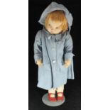 A 20th century stuffed fabric doll, dressed in blue overcoat with bonnet, on metal stand, 75cm tall