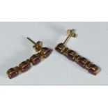 A pair of 15ct gold drop earrings each claw-set with four oval rubies and six small diamonds. The