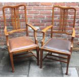 A pair of oak carver chairs with rail backs, dark brown leather upholstered drop-in seats and raised