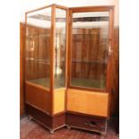 A mid-20th century lockable glass display cabinet, with storage cupboard beneath, on ball castors,