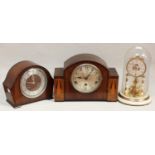 A German anniversary clock with glass dome, together with an Art Deco walnut mantel clock and a