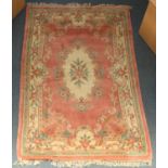 A large machine-made Chinese rug with central floral cartouche and floral borders decorated in