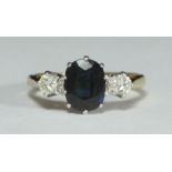 An 18ct gold three-stone ring claw-set with a central oval sapphire and two RBC diamonds. The