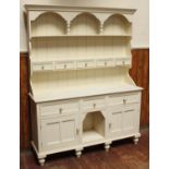 A white painted pine dresser with galleried top and planked back above a shelf, with five drawers