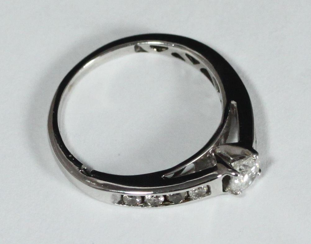 An 18ct white gold solitaire diamond ring four claw-set with a round RBC diamond and channel set - Image 2 of 2