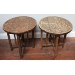 Two African carved occasional tables, each with round tops carved in relief with scenes of