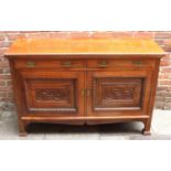 An Edwardian walnut sideboard with two frieze drawers, above a pair of carved panelled doors, raised