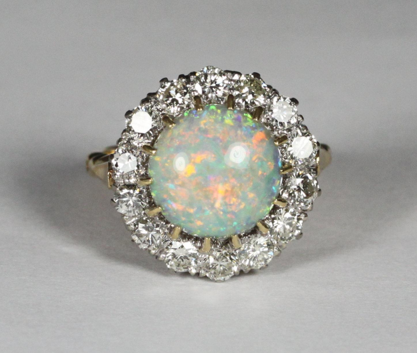 An 18ct gold cluster ring claw-set with a central round opal surrounded by fourteen round