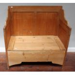 A pine settle of typical form, the seat lifting to reveal storage space, raised on squared supports,