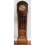 A 1920s carved oak longcase clock with spring driven ticking and chiming movement, glazed central