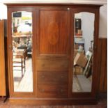 A large Edwardian inlaid mahogany wardrobe, the shaped cornice over a central cupboard door, above