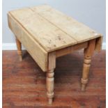 A pine Pembroke style dining table with two drop-leaves, single frieze drawer and raised on turned