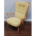 An Ercol Windsor armchair in light beech, with curved stick back and raised on turned supports,