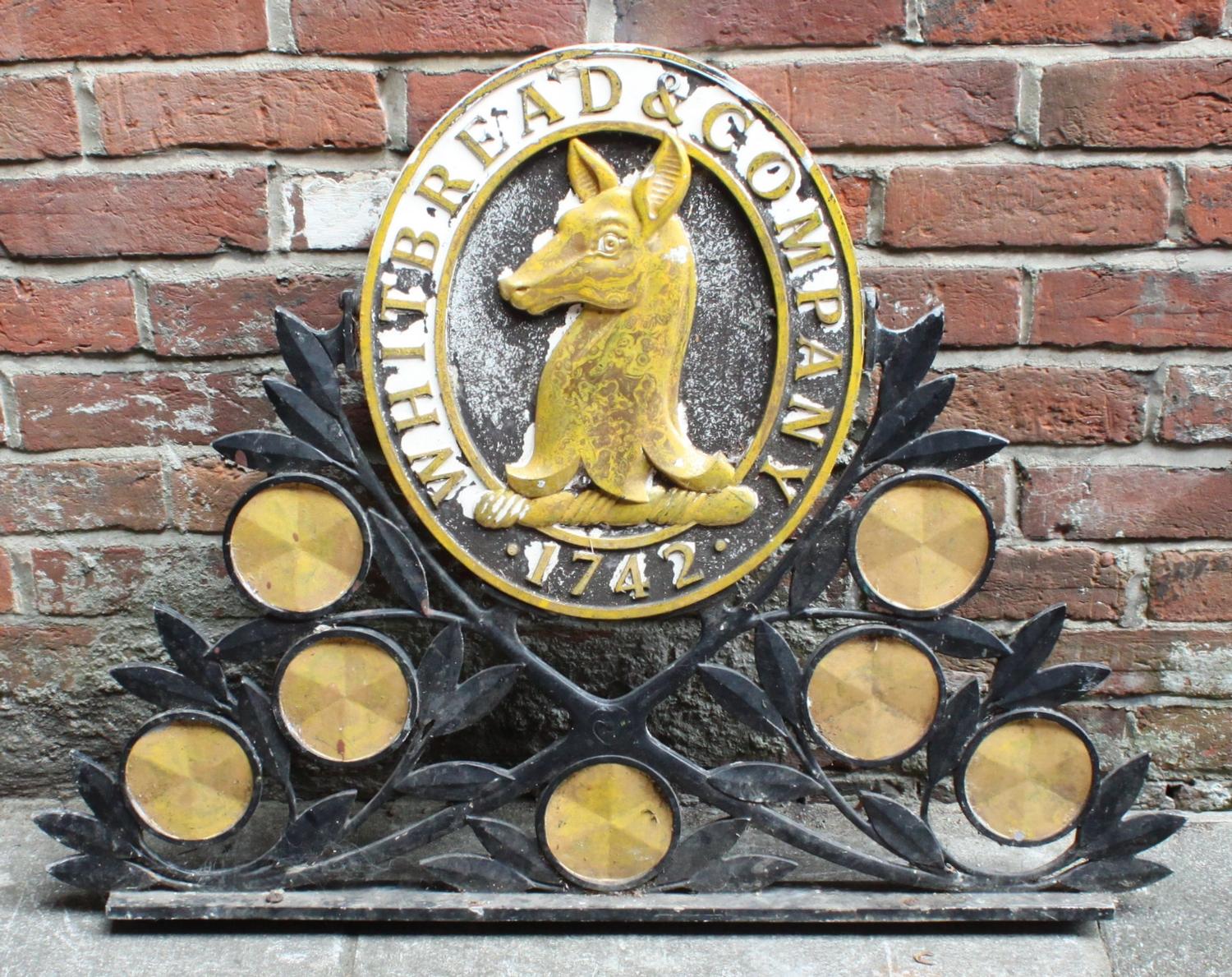 A large cast metal 'Whitbread & Company 1742' sign, painted in black and gold, the central oval