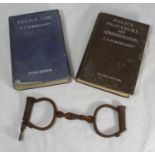 A pair of early 20th century police handcuffs complete with key, together with two books by C.C.H.