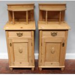 A pair of pine bedside pot cupboards, the raised backs with shelf above a single drawer and carved