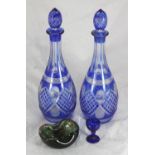 A pair of Bohemian blue cut glass decanters and acorn stoppers, together with a green glass and foil
