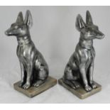 A pair of silvered terracotta sculptures modelled as Egyptian temple dogs, raised on pedestal bases,