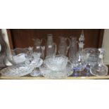 A shelf of assorted mixed glassware comprising four jugs, two decanters, candlesticks and various