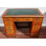 An oak pedestal desk with gilt-tooled green leather scribe to top and three frieze drawers, raised