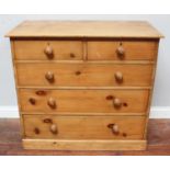 A stripped pine chest of two short and three long graduated drawers with turned pulls, on plinth