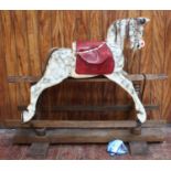 An Edwardian dapple-grey rocking horse with red studded saddle, raised on trestle base approx. 140cm