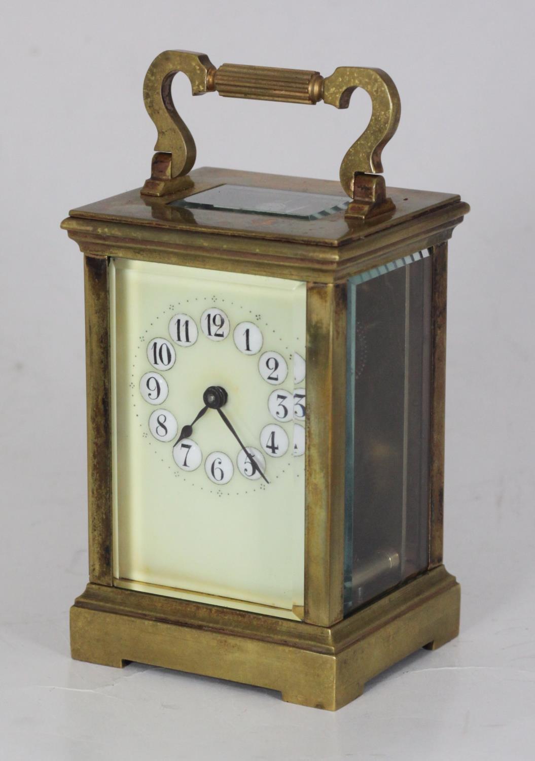 A brass carriage clock, the top with platform escapement, the ivory coloured dial with Arabic