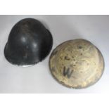 A British Army helmet circa 1982 with replacement liner, together with a Warden's helmet with