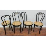 A set of four black painted hoop-back bentwood chairs with caned seats