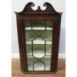 A George III mahogany hanging corner cupboard, with swan-neck pediment, astragal glazed door,