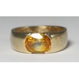 A 9ct gold wide band solitaire ring set with an oval yellow sapphire weighing 2.50cts, total