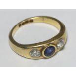 An 18ct gold ring rub-over set with a central round sapphire and gypsy set with a diamond to each
