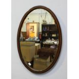 An Edwardian oval bevelled mirror with marquetry inlaid detail, approx. 79cm