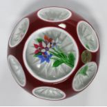 A Saint Louis Glass paperweight, opaque white and red cased glass over clear with floral feature,