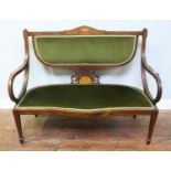 An Edwardian inlaid mahogany settee, with green fabric upholstery and frilled gimp, raised on