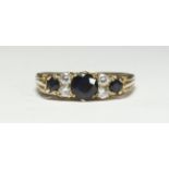 A 9ct gold ring set with three sapphire coloured stones and four diamonds, total diamond weight